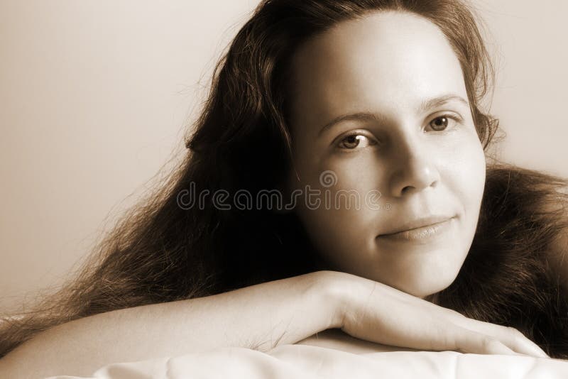 Woman lying in bed with eyes closed in serene dreamy relaxation, soft sensual expression during hypnotic guidance