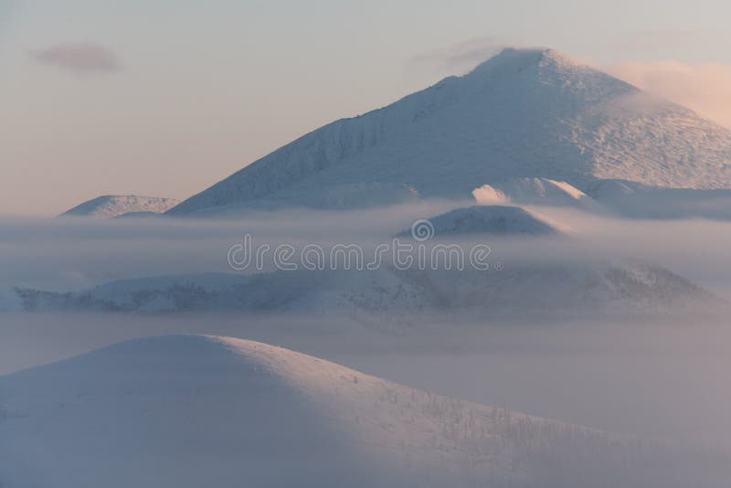 Morning landscape of snow-capped mountains. Foggy landscape of the coldest place on Earth - Oymyakon