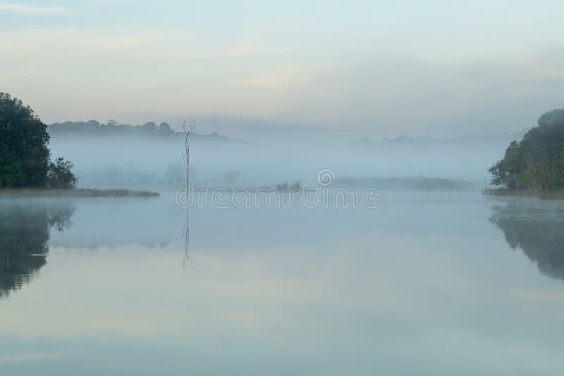 Morning mist hang low over lake during winter stock photo Morning mist hang low over lake during winter stock photo