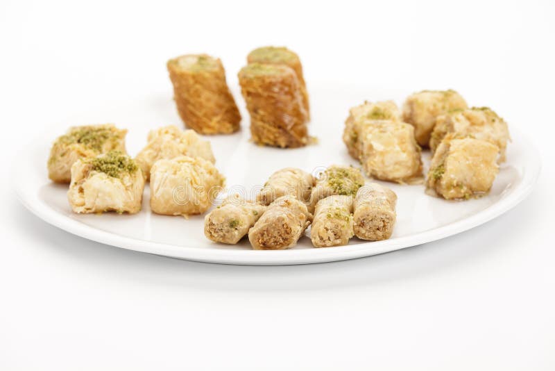 Crunchy Assabeh cashew baklava pieces arranged on a white plate. Dainty sweet dessert morsels made of flaky pastry as served in Middle Eastern cuisine. Closeup studio shot on bright table top. Crunchy Assabeh cashew baklava pieces arranged on a white plate. Dainty sweet dessert morsels made of flaky pastry as served in Middle Eastern cuisine. Closeup studio shot on bright table top.