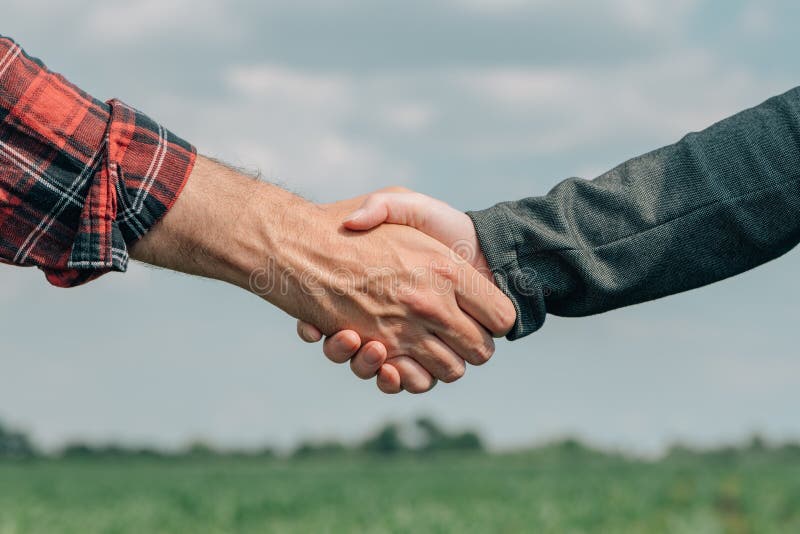 Mortgage loan officer and farmer shaking hands upon reaching an agreement