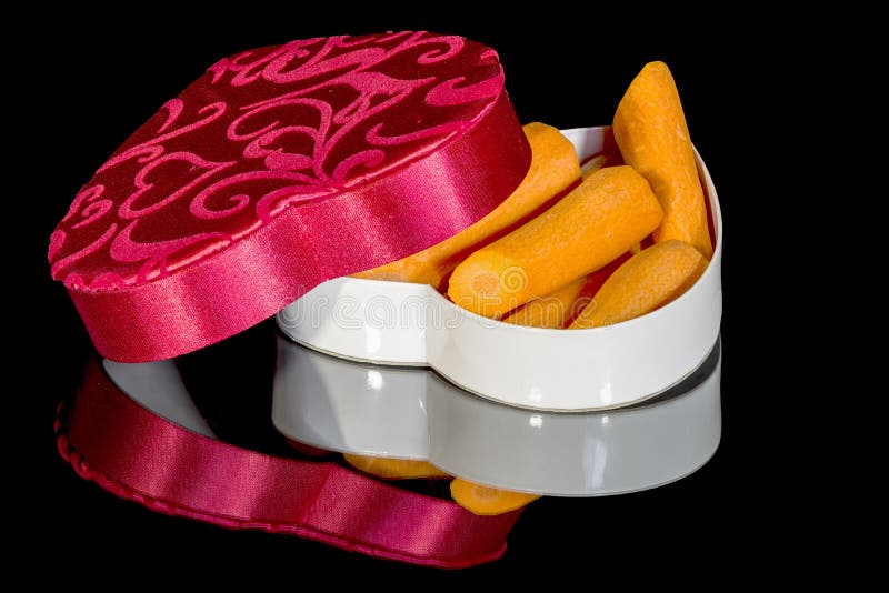 Morötter i en godis boxas använt för valentins dag arkivfoton Morötter i en godis boxas använt för valentins dag arkivfoton