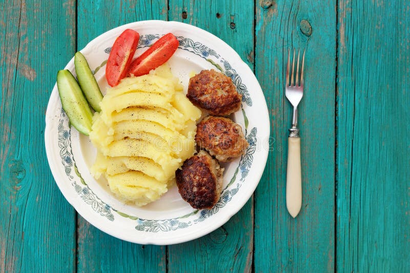 Mosade potatisar och tre hemlagade köttkotletter med ny cucumbe royaltyfri fotografi Mosade potatisar och tre hemlagade köttkotletter med ny cucumbe royaltyfri fotografi