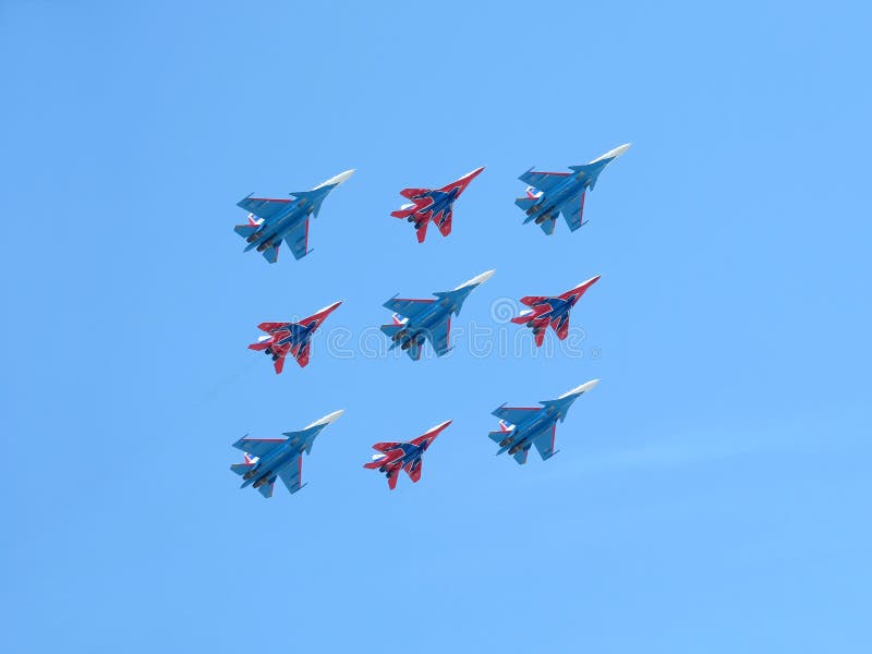 MOSCOW, RUSSIA - MAY 9, 2018: Aerobatic groups Russian Knights and Swifts on MIG-29 and SU-27 fighters demonstrates Kubinsky Diamond in flight against blue sky on parade flight on May 9, 2018. MOSCOW, RUSSIA - MAY 9, 2018: Aerobatic groups Russian Knights and Swifts on MIG-29 and SU-27 fighters demonstrates Kubinsky Diamond in flight against blue sky on parade flight on May 9, 2018