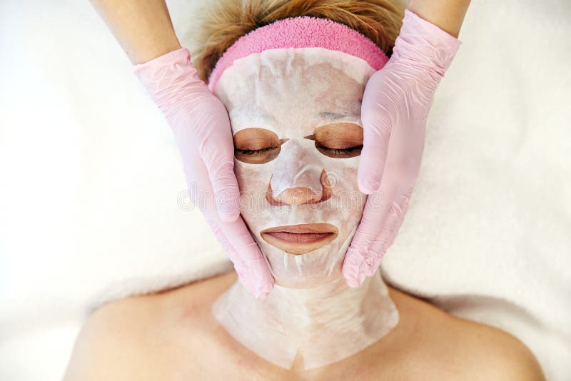 Moscou, Rússia, 02 02 2019: Mulher bonita com máscara facial no salão de beleza Aplicando a máscara facial na cara da mulher em foto de stock Moscou, Rússia, 02 02 2019: Mulher bonita com máscara facial no salão de beleza Aplicando a máscara facial na cara da mulher em foto de stock