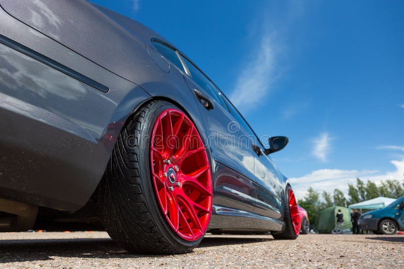 Sobriquette redde Glad Gray Car with Lowered Suspension and Bright Red Forged Wheels is on the  Parking. Against Blue Sky Stock Image - Image of forged, closeup: 160367053