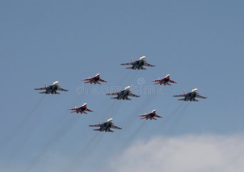 The `Strizhi` and `Russian Knights` aerobatic teams are flying in the sky over Red Square during the parade.