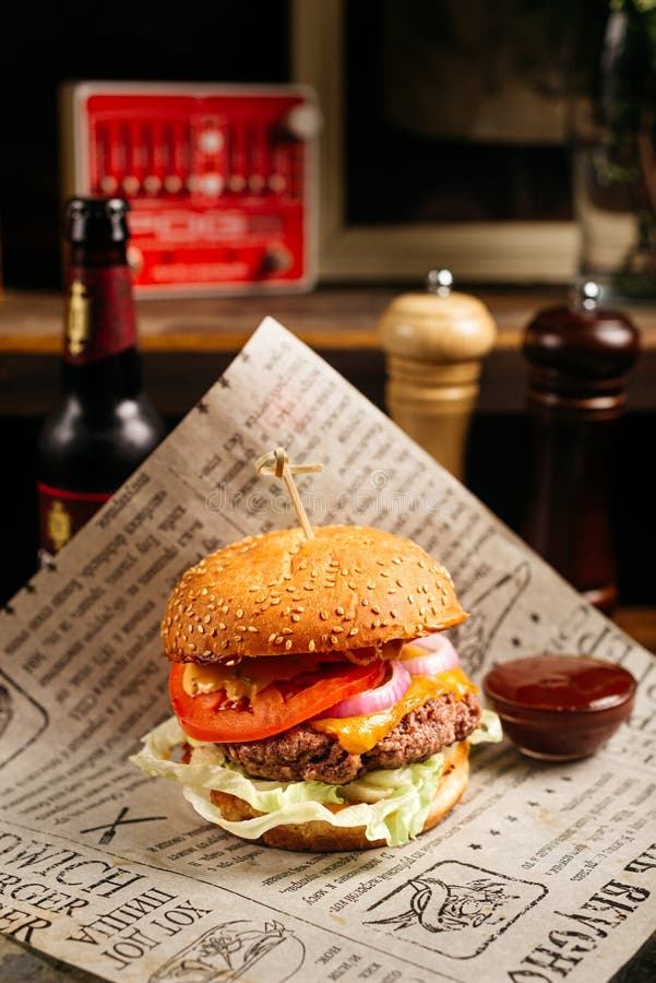 Moscow, Russia - October 07 2020: Beef burger portion on a craft paper on pub table. Wooden interior of a bar stock photo Moscow, Russia - October 07 2020: Beef burger portion on a craft paper on pub table. Wooden interior of a bar stock photo