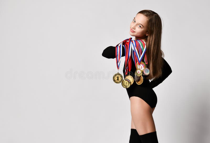 Moscow, Russia, October 2019 girl gymnast in black sport body and uppers walking backwards with many gold medals on shoulder