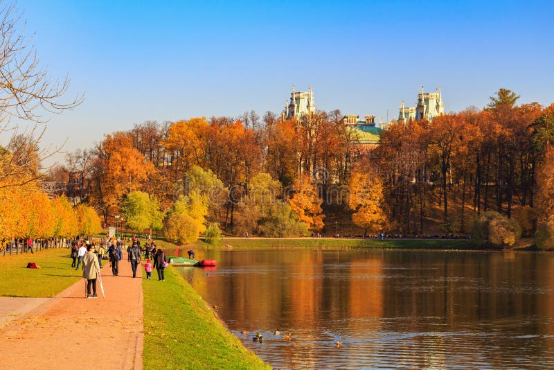 Moscow, Russia - October 17, 2018: People walking on alley on pond shore at sunny autumn day in Tsaritsyno park in Moscow