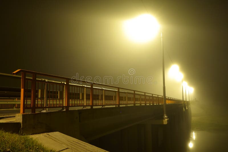 Bridge over the river and the wreathed light of street lamps in heavy fog at night royalty free stock photo Bridge over the river and the wreathed light of street lamps in heavy fog at night royalty free stock photo