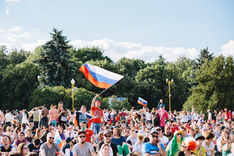 MOSCÚ, RUSIA - JUNIO DE 2018: Un fanático del fútbol agita una bandera nacional rusa en una muchedumbre en la zona de la fan dura imagenes de archivo MOSCÚ, RUSIA - JUNIO DE 2018: Un fanático del fútbol agita una bandera nacional rusa en una muchedumbre en la zona de la fan dura imagenes de archivo