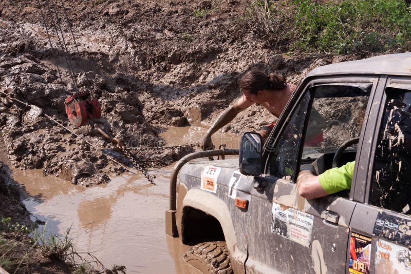 Moskau, Russland - 25. Mai 2019: Ein Mann befestigt eine Kette an einem Auto, das im Schlamm gehaftet wird Und isuzy Soldat nicht lizenzfreie stockfotografie Moskau, Russland - 25. Mai 2019: Ein Mann befestigt eine Kette an einem Auto, das im Schlamm gehaftet wird Und isuzy Soldat nicht lizenzfreie stockfotografie