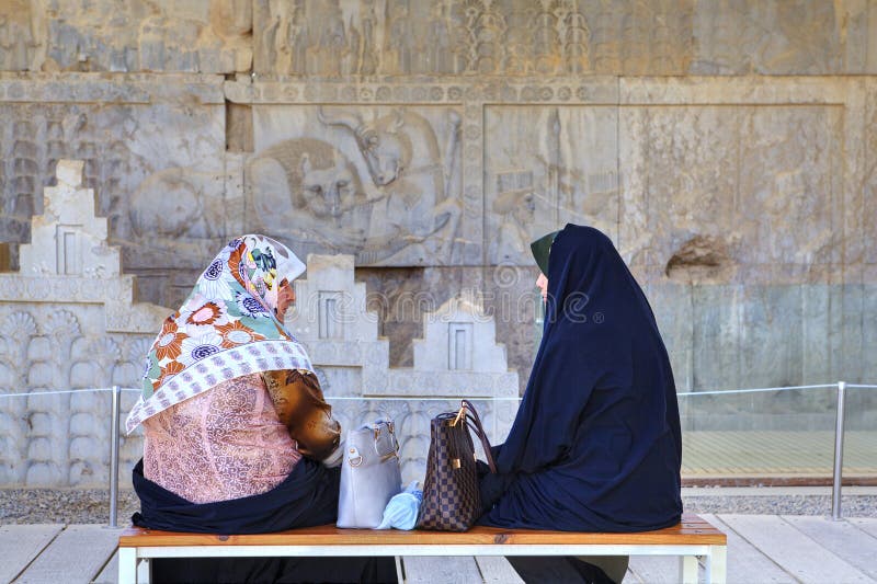 Moslimvrouwen die terwijl het zitten op bank in Persepolis-museum spreken stock foto Moslimvrouwen die terwijl het zitten op bank in Persepolis-museum spreken stock foto