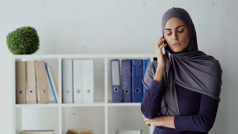 Moslimzakenvrouw die een telefoongesprek voert met haar werknemer