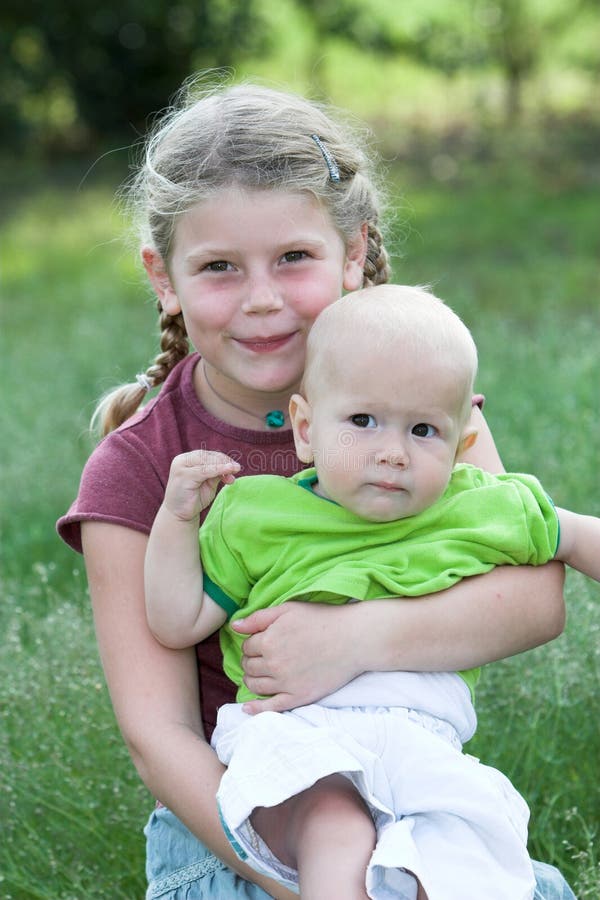 Young girl holding her baby brother in her arms. Young girl holding her baby brother in her arms
