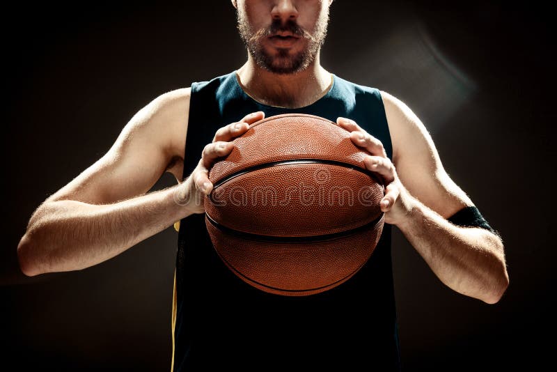 Mostre em silhueta a opinião um jogador de basquetebol que guarda a bola da cesta no fundo preto imagens de stock Mostre em silhueta a opinião um jogador de basquetebol que guarda a bola da cesta no fundo preto imagens de stock