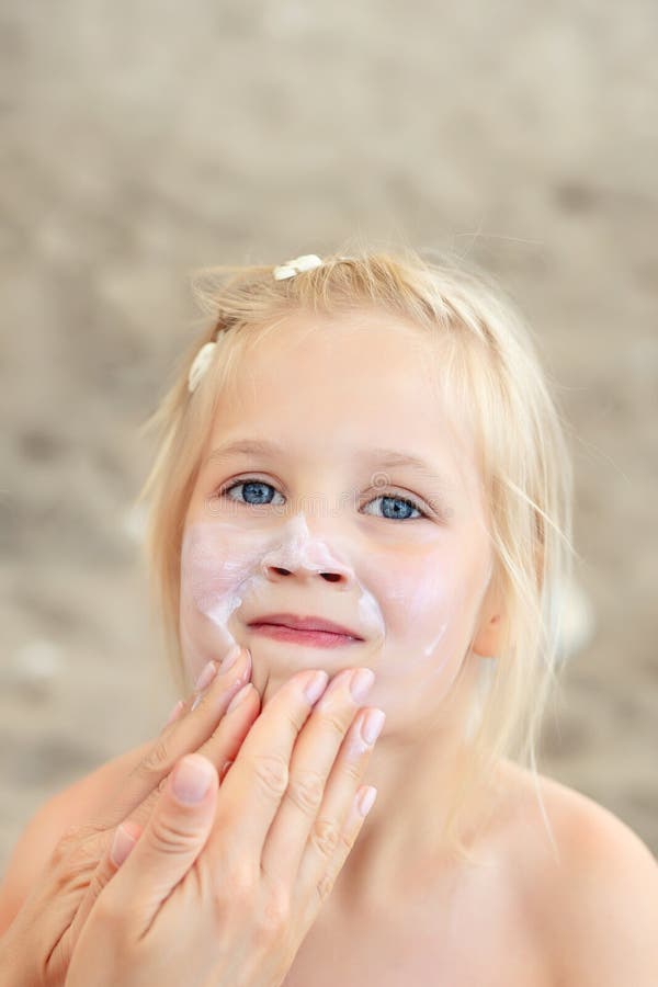 Mother applying sunscreen protection creme on cute little daughter face. Mom using sunblocking lotion to protect kid girl from sun stock photo Mother applying sunscreen protection creme on cute little daughter face. Mom using sunblocking lotion to protect kid girl from sun stock photo