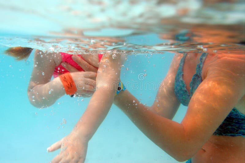 Young girl swimming in mother arms.