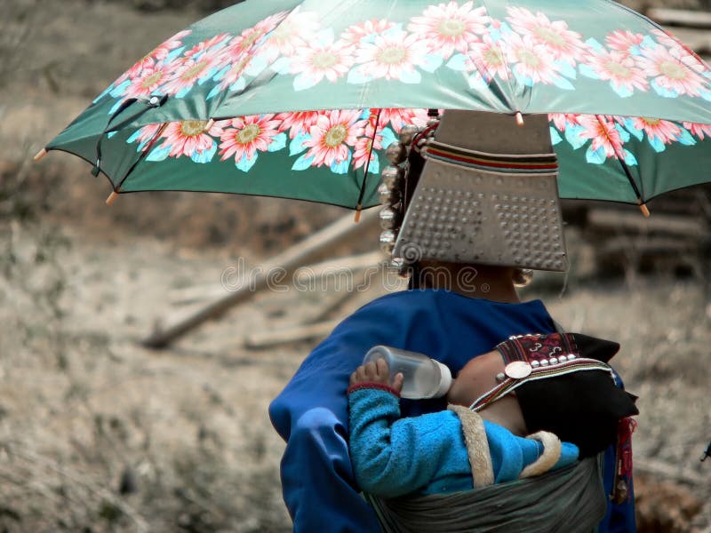 Mother and baby from Akha Hill Tribe, sheltering from hot sun, Num Lin Mai village, Myanmar (Burma).