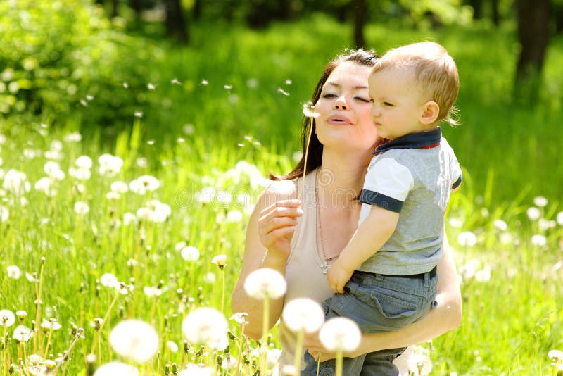 Mother and baby boy blowing on a dandelion.