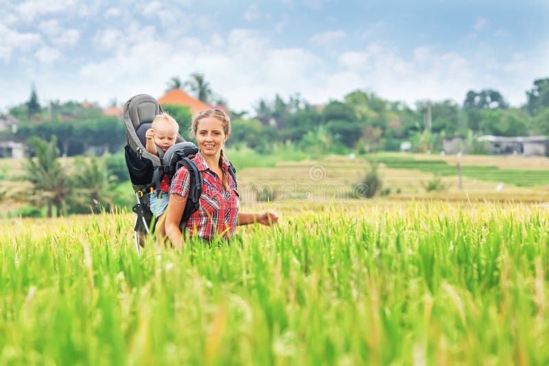 Mother with baby in carrying backpack walking on rice terraces