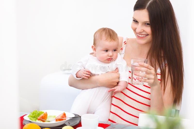 Mother and Baby eating at Home. Happy Smiling Family Portrait