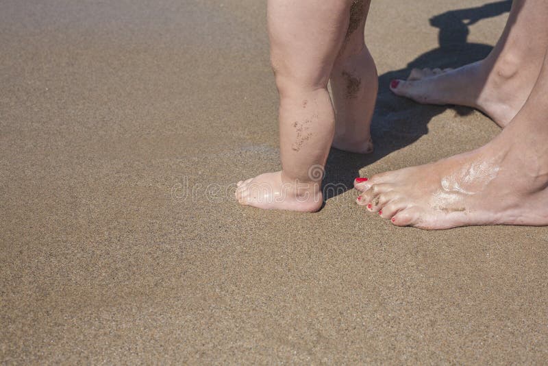Mother and baby feet walking on sand beach royalty free stock images