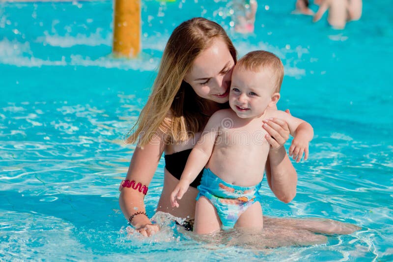 Mother and baby in swimming pool. Parent and child swim in a tropical resort. Summer outdoor activity for family with kids.