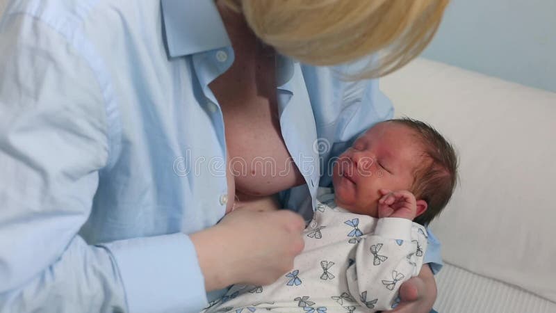Mother Breast Feeding and Hugging Her Baby.Young Mother Feeding Breast Her Babyboy at Home in Blue-white Room. Mom Stock Footage - Video of lactating, family: 134883316