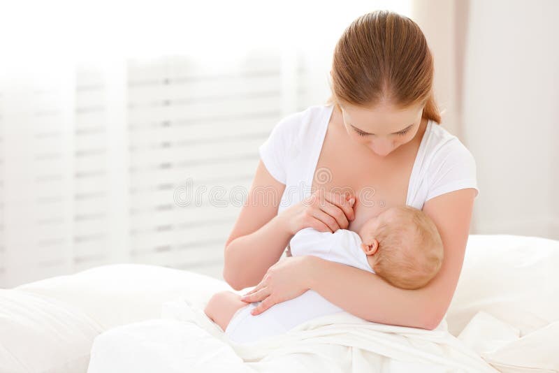 La madre l'allattamento al seno il suo bambino appena nato in un letto bianco.