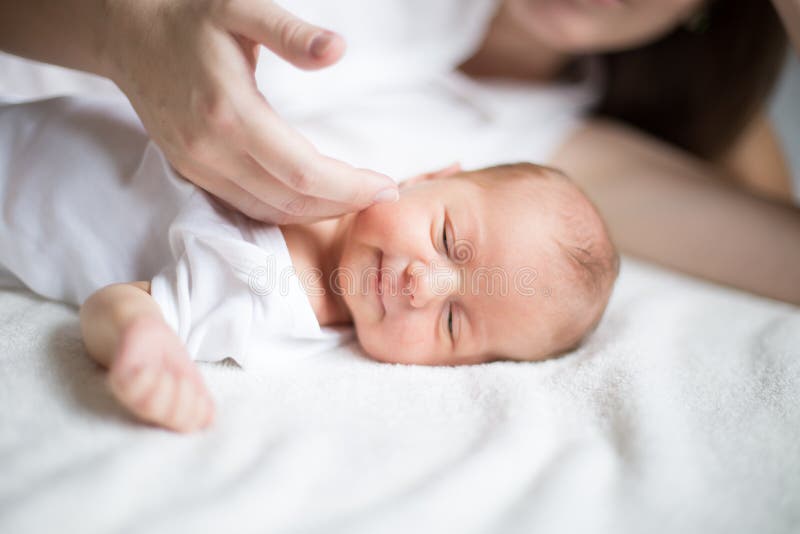 Mother caressing a newborn baby lying on the bed