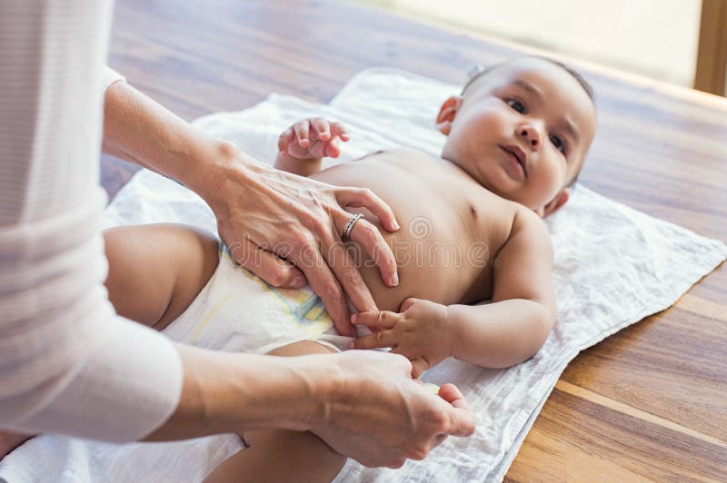 Mother hands changing baby nappy. Mother putting diaper on her hispanic son lying in nursery. Close up of mother giving baby diaper change at home. Mother hands changing baby nappy. Mother putting diaper on her hispanic son lying in nursery. Close up of mother giving baby diaper change at home.