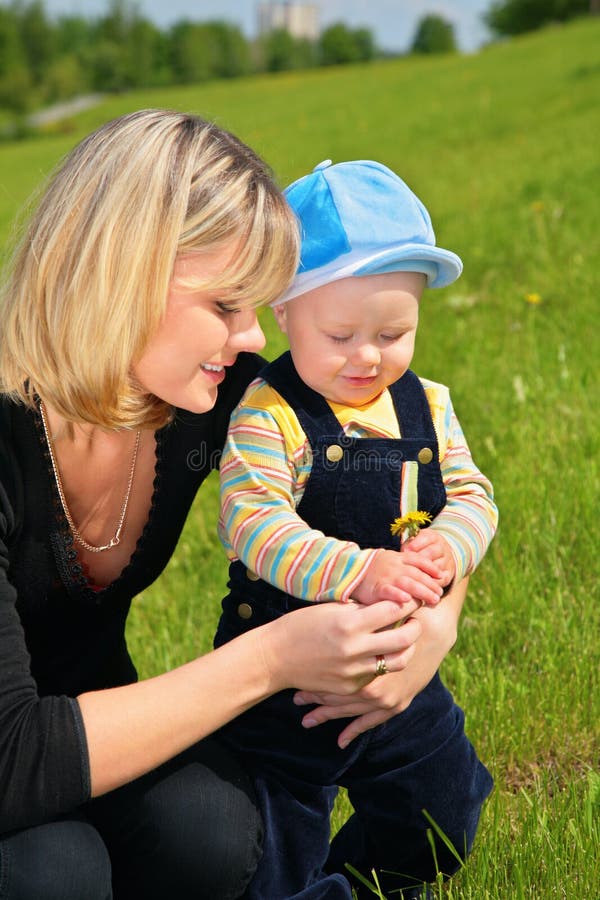 Mother with child and dandelion on summer meadow