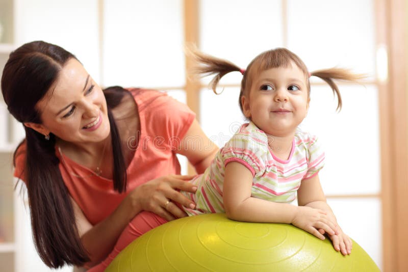 Mother and child playing with gymnastic ball at home