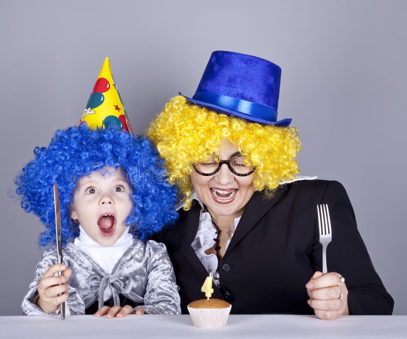 Mother and child in funny wigs and cake. At birthday. Studio shot royalty free stock photography Mother and child in funny wigs and cake. At birthday. Studio shot royalty free stock photography