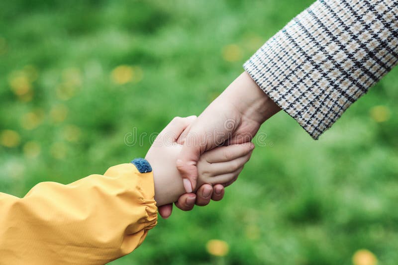 Mother and child hands holding each other on field. Support, help and trust. Kid and mother hands on nature background. Love, relationship and teamwork in family