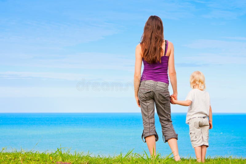 Mother and child holding hands by the ocean