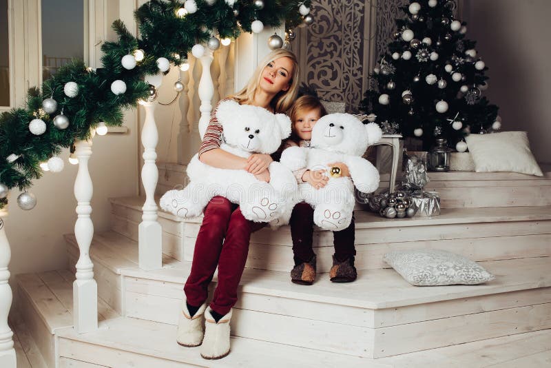 Mother and child hugging white teddy bear and posing