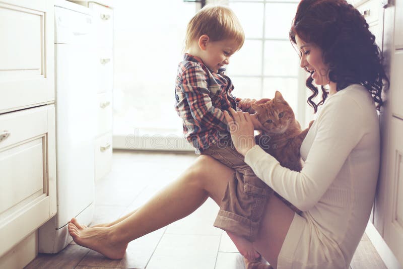 Mamma con il suo bambino che gioca con il pet sul pavimento in cucina a casa.