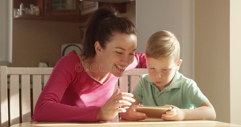 Mother and Child Playing on a Mobile Phone at the Table Having a Good Time Together
