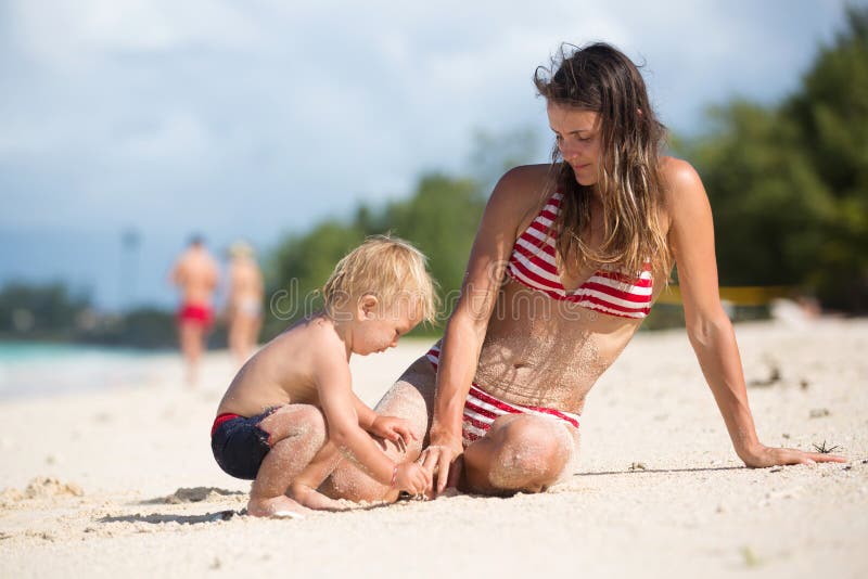 Mother and child playing at tropical beach. Family sea summer vacation. Mom and kid, toddler boy, play in the water. Ocean and