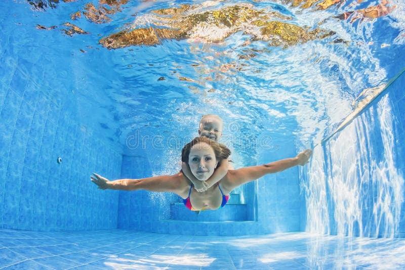Mother with child swimming and diving underwater in pool stock photos