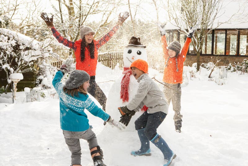 Madre a divirtiéndose el edificio muneco de nieve en el jardín.