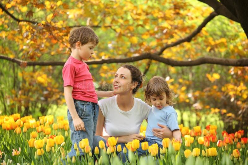 Mother with children in garden among tulips