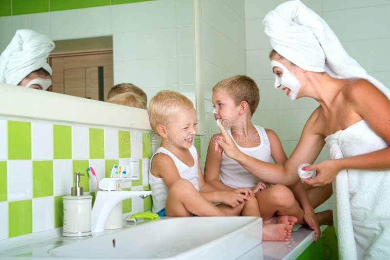 Mother and children make a face mask in the morning. The boys joke with mom. royalty free stock photography Mother and children make a face mask in the morning. The boys joke with mom. royalty free stock photography