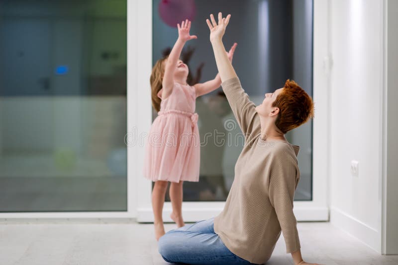 Mother and cute little daughter playing with balloons