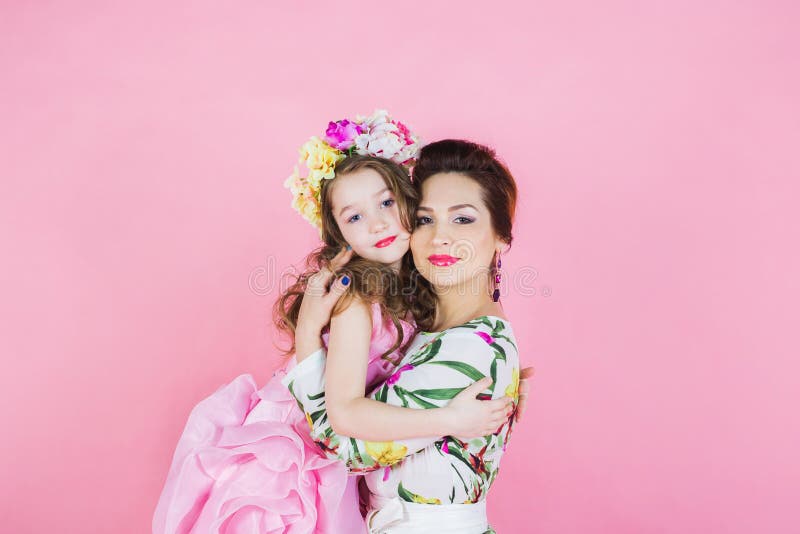 Mother and daughter in bright dresses on a pink background stock images Mother and daughter in bright dresses on a pink background stock images
