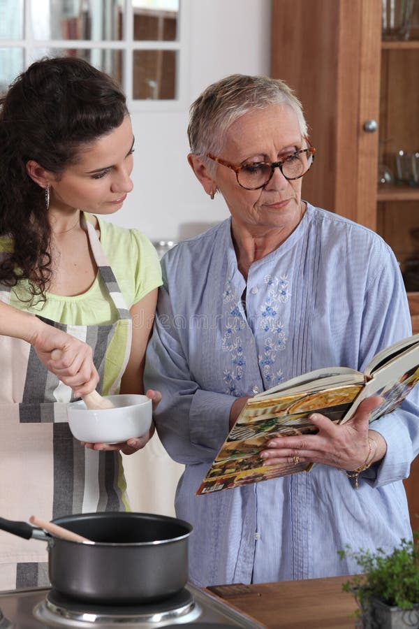 Mother and daughter cooking stock images