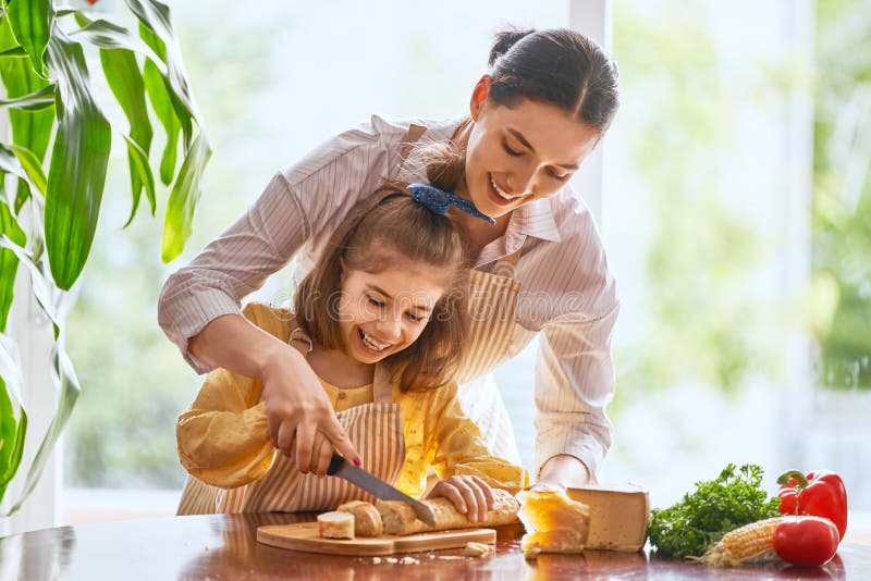 Mother and daughter cutting bread and cheese